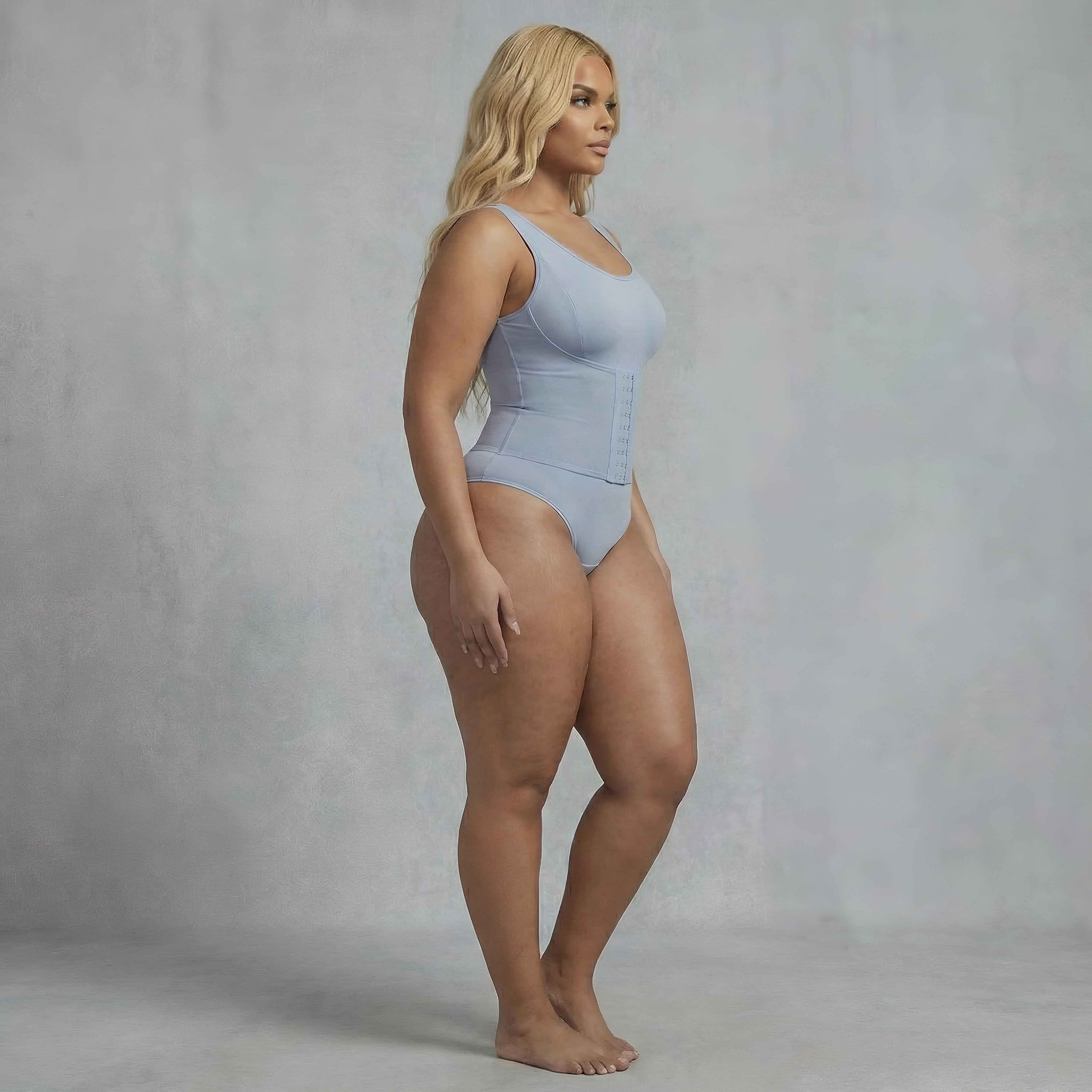 Woman wearing a light blue swimsuit against a gray background. Blue shapewear curvy bodysuit lyvia.