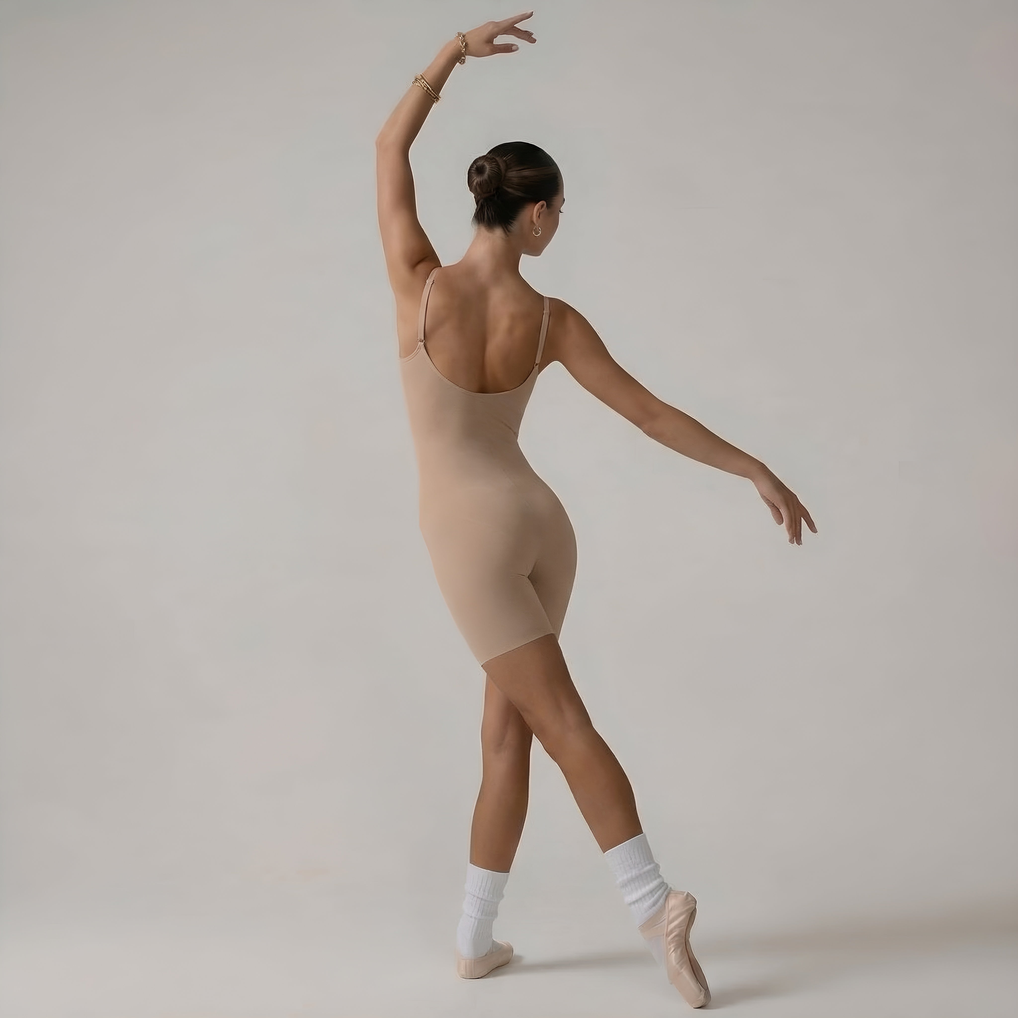 Ballerina in a beige leotard posing against a plain background. Back view womans shapewear beige bodysuit lyvia.