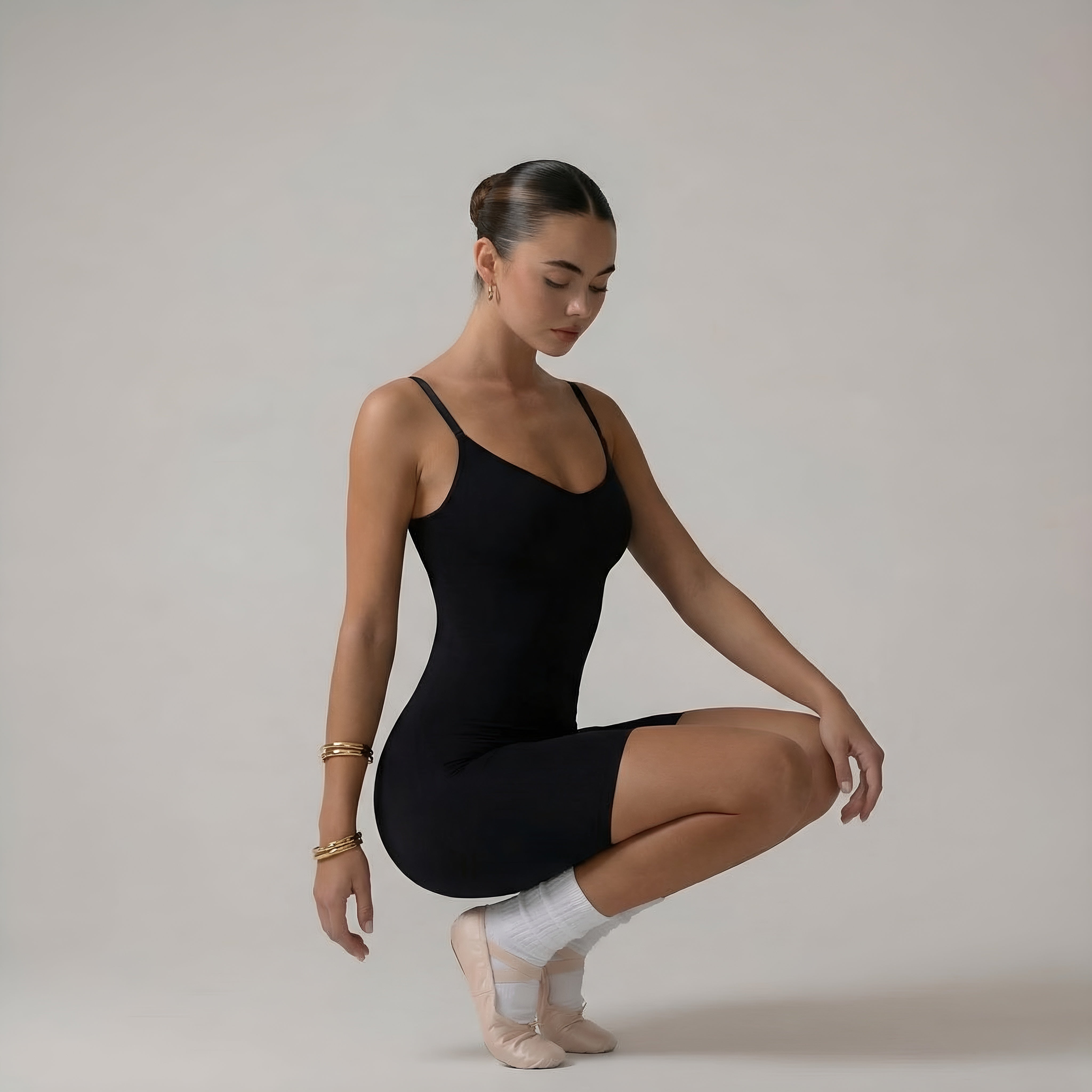 Dancer in a black leotard and white socks posing against a plain background. Black shapewear womans bodysuit lyvia.