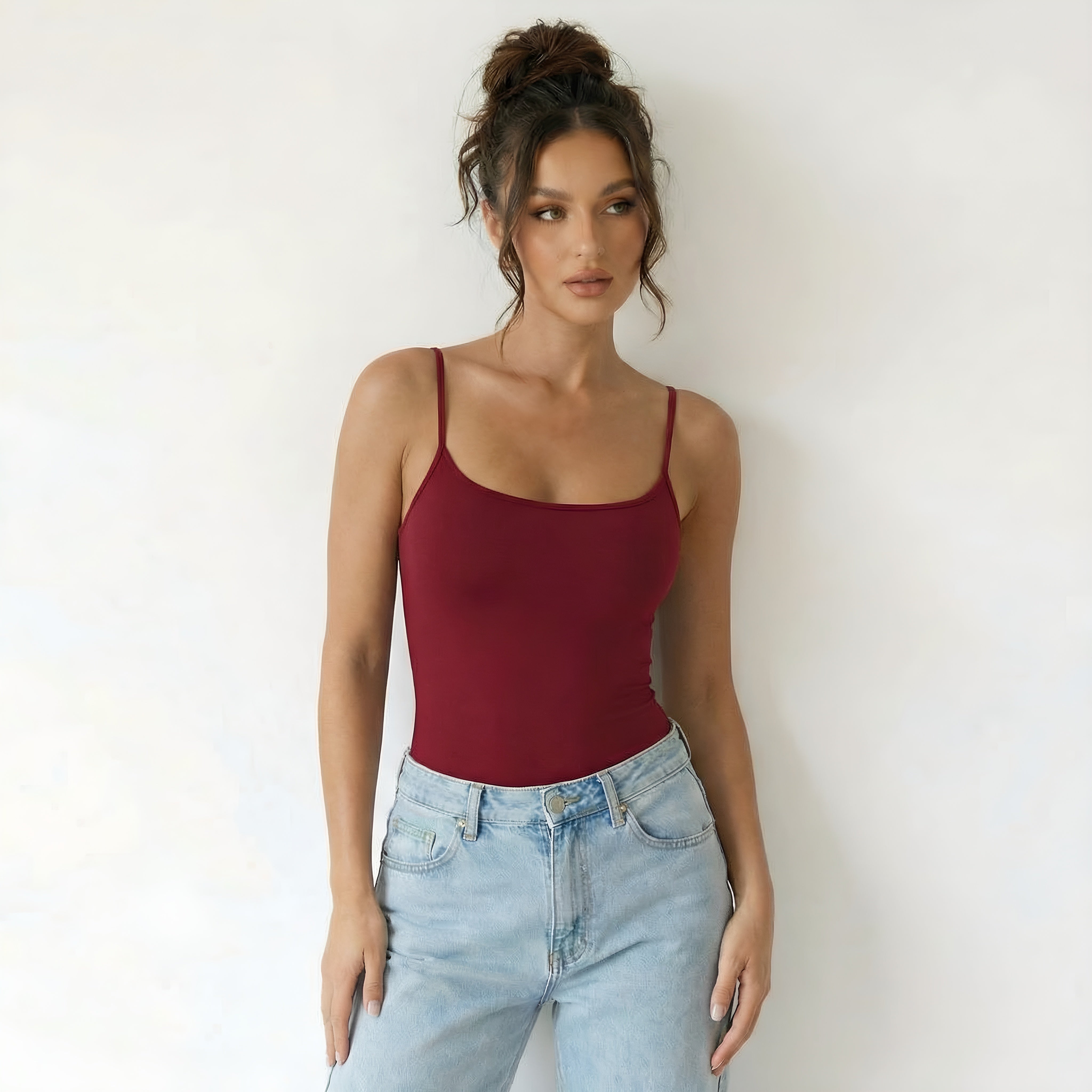 Woman wearing a red tank top and light blue jeans against a white background woman wearing red shapewear top lyvia.